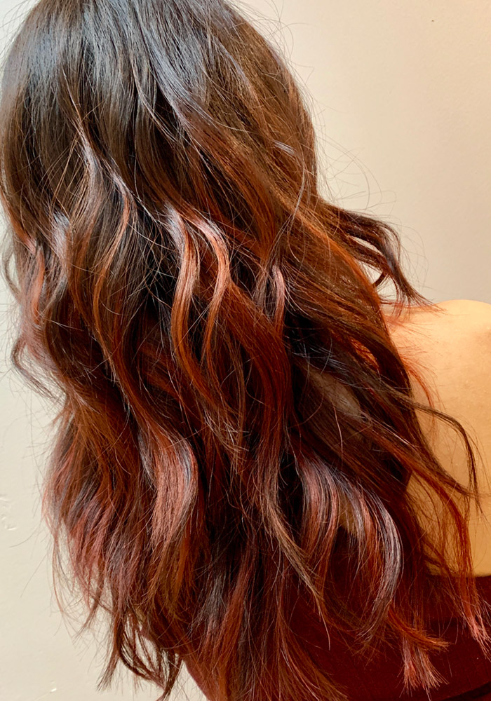 Long wavy hair with balayage and copper red highlights, seen from behind
