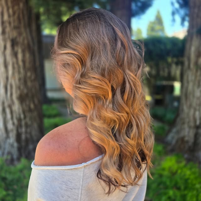 Long wavy hair with warm caramel tones by Ashleah Byram at Salon Bravissimo