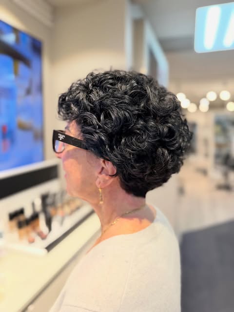 Short, dark curly haircut seen in profile