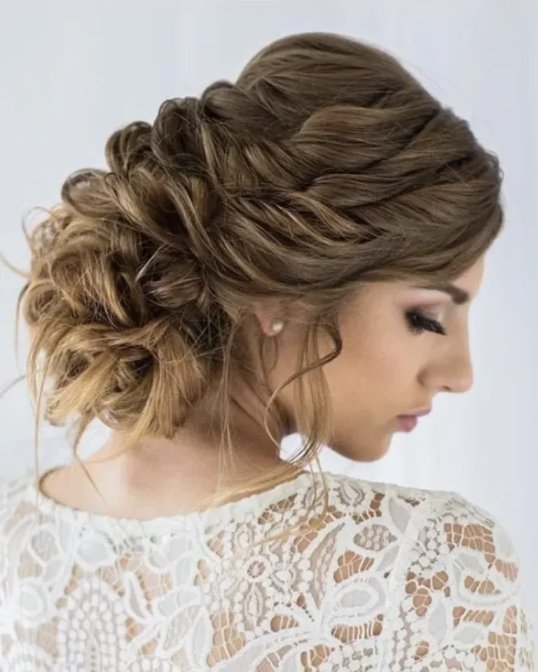 Soft braided bridal updo in brown hair with golden highlights, side view with a white lace top