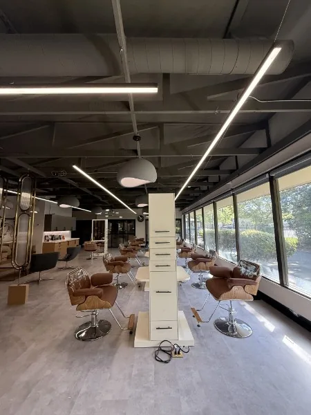 A row of styling chairs beside floor-to-ceiling windows at Salon Bravissimo on Howe Ave, Sacramento